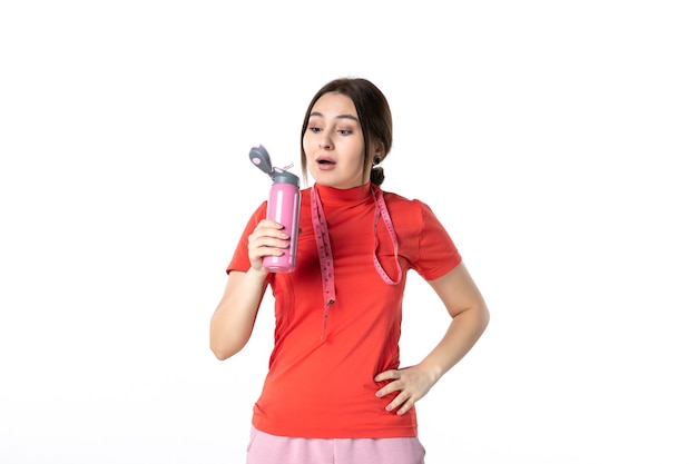 Top view of a focused young girl in redorange blouse holding metre and thermos on white background