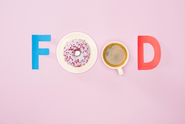 一杯のコーヒーとピンクのジャンク フードの背景に分離されたドーナツから作られた食品単語のトップ ビュー