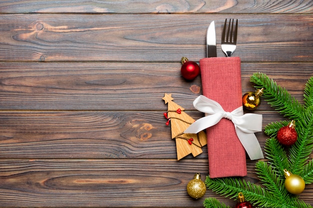 Vista superiore della forcella e del coltello sul tovagliolo con le decorazioni di natale e l'albero del nuovo anno sul concetto di legno, di festa e festivo