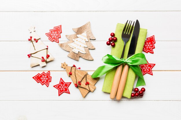 Top view of fork and knife tied up with ribbon on napkin. Close up of christmas decorations and New Year tree. Happy holiday concept