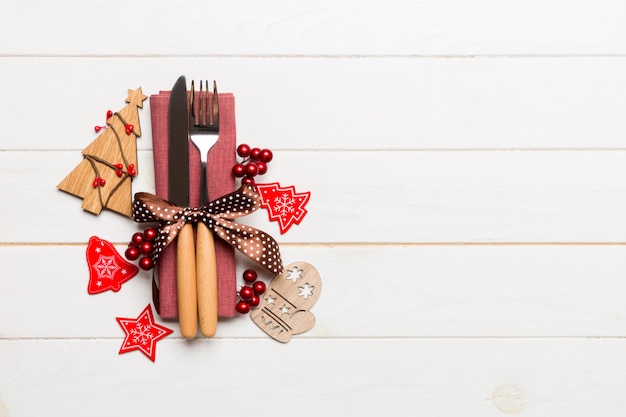 Top view of fork and knife tied up with ribbon on napkin on wooden background. Christmas decorations and New Year tree. Happy holiday  with empty space 