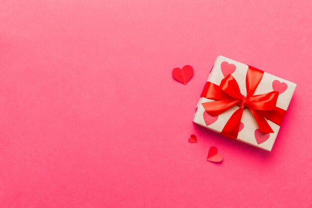 Top view foto van valentijnsdag decoraties geschenk doos met rode lint boog op gekleurde achtergrond Holiday geschenk dozen met top view