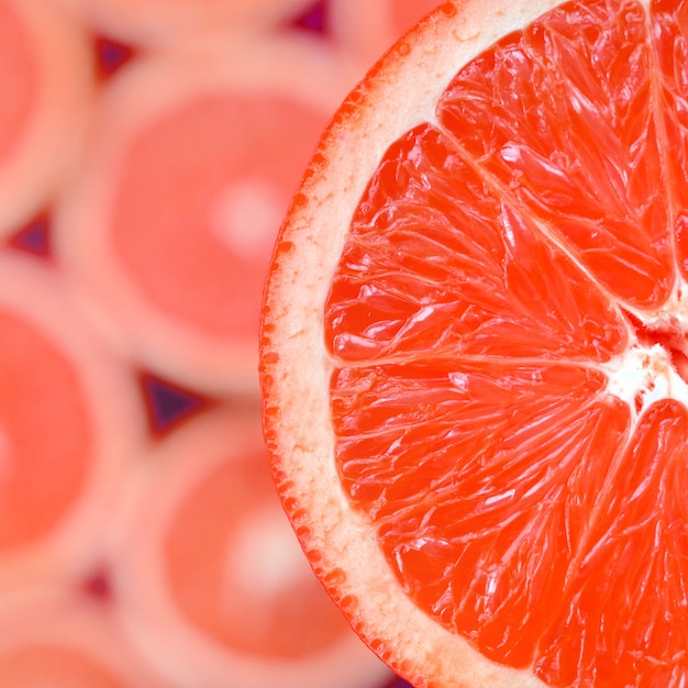 Top view of a fragment of the red grapefruit slice on the background