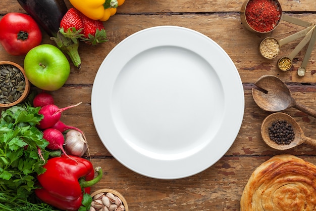 Vista dall'alto del telaio vari prodotti, erbe, spezie orientali, piatto bianco con spazio per il testo su sfondo di legno invecchiato, orizzontale, layout, copia spazio, concetto di alimentazione sana, mockup