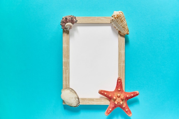 Top view of frame with seashells and starfish on blue. Summer vacation concept. Sea flat lay