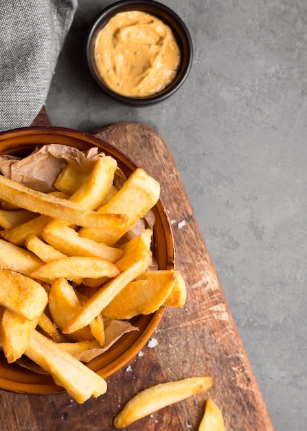 Top view of french fries in bowl with salt and mustard