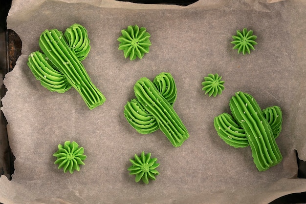 Photo top view french meringue cookies, in the form of cactus. homemade meringue on baking sheet.