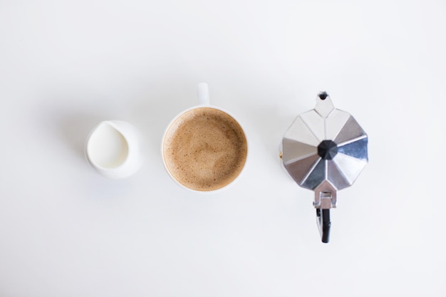 Photo top view of french press cup of coffee and milk jar standing in row isolated on white