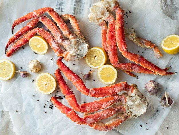 Top view of fresh crab phalanges with lemon and spices on rumpled paper.