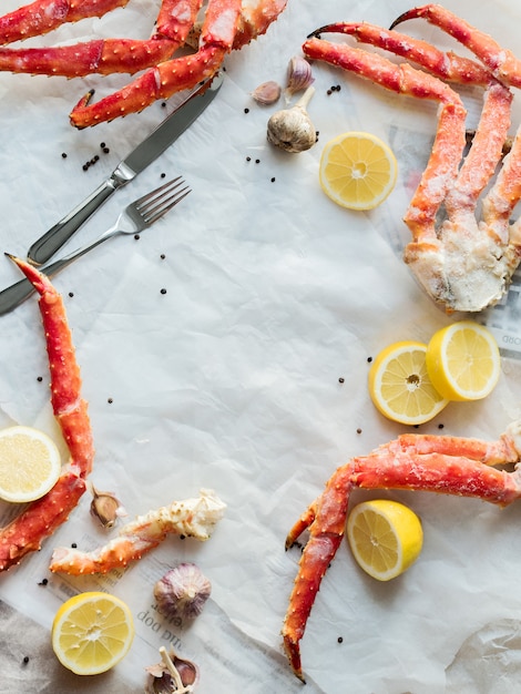 Top view of fresh crab phalanges with lemon and spices on rumpled paper.