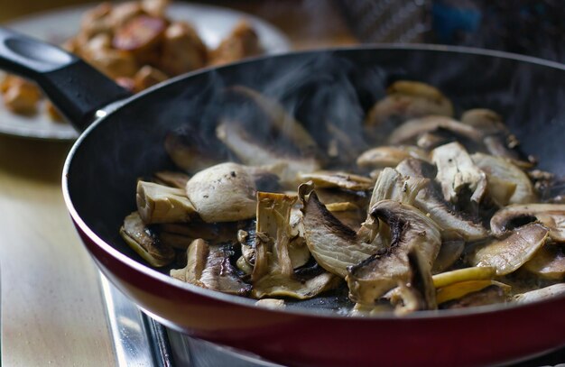 Top view of fresh cut mushroom are being cooked in fry pan with steam coming out showing home cooked