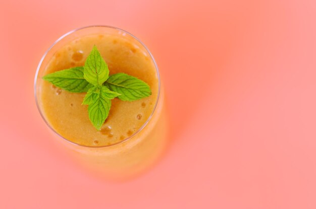 Top view of fresh delicious smoothie in a glass made of peach banana with mint creative concept