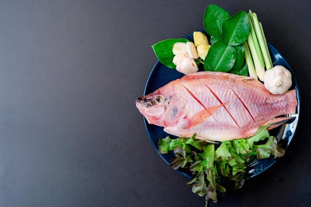 Top view of fresh fish and vegetables in ceramic dishes prepared for cooking with copy space