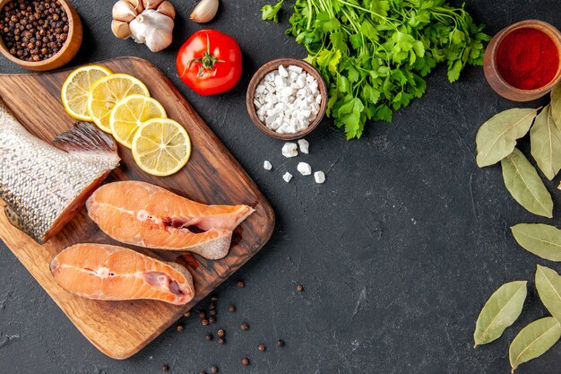 Vista dall'alto pesce fresco con verdure e limone sullo sfondo scuro insalata di pesce acqua carne oceano mare pasto cena frutti di mare