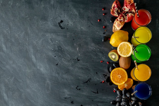 Top view of fresh juice variety, different fruits around, copy space for your text on a black tables