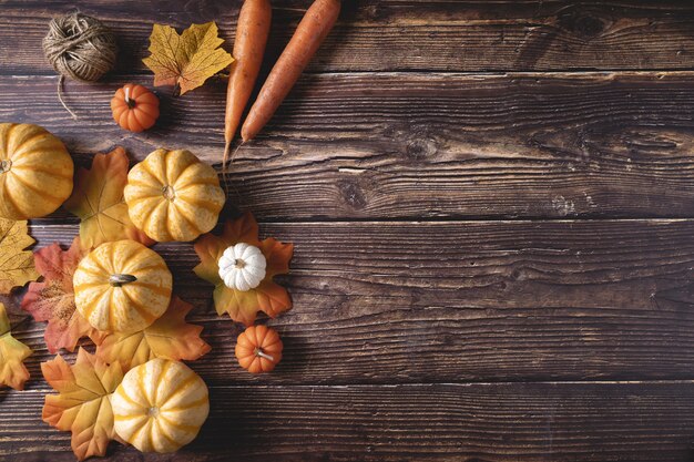 Photo top view of fresh pumpkins, carrots, and autumn leaves on a wooden surface