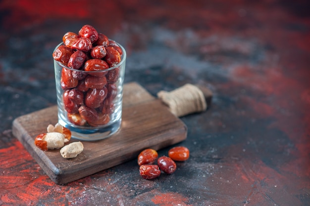 Photo top view of fresh raw silverberry fruits inside and outside of a glass on a wooden cutting board on the right side on mix colors background