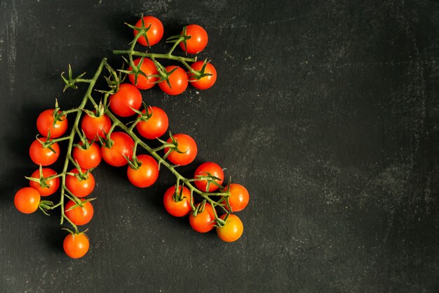 Top view of fresh ripe cherry tomatoes on black background with copy space. Ingredient for mediterranean cuisine.