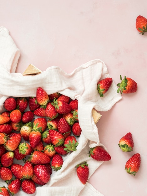 Top view of fresh ripe strawberries in wooden box on pastel background