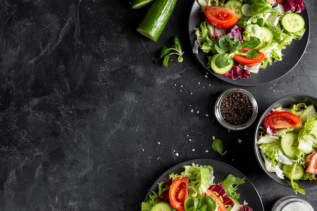 Top view fresh salads on dark plates with copy space