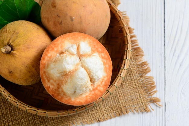 Top view of Fresh Santol fruits on bamboo basket and on white wood background