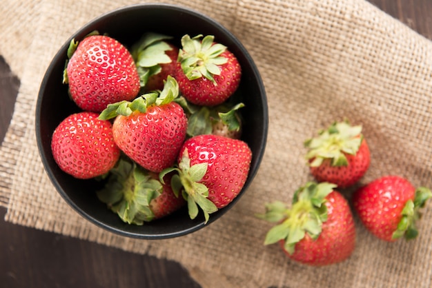 Top view fresh strawberries in a bowl on wood