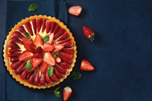 Top view of fresh strawberry tart on blue background