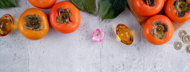 Top view of fresh sweet persimmons kaki with leaves on gray table for chinese lunar new year concept, the word means spring is coming