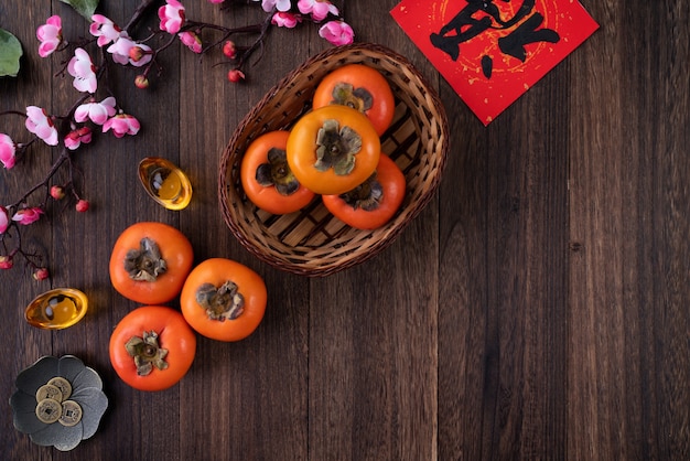 Top view of fresh sweet persimmons kaki with leaves on wooden table background