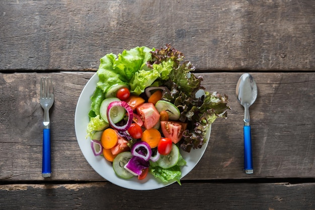 Top view of fresh vegetable salad on wooden background