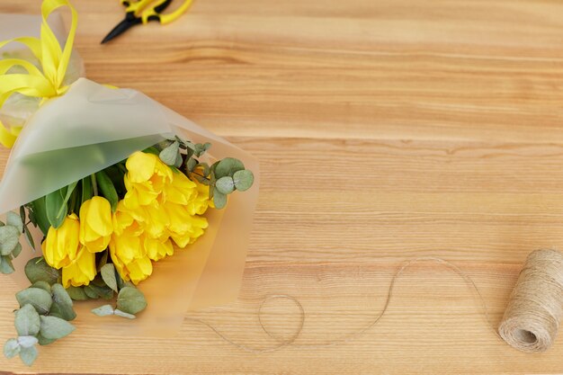 Top view of fresh yellow tulips bouquet on wooden rustic table. Spring flowers. copy space