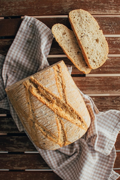 top view of freshly baked bread loaf on rustic wooden cutting board and napkin