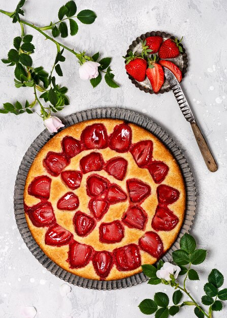 Top view of freshly baked curd cake with strawberries on light grey background. Delicious homemade sweet food concept. Copy space.