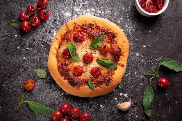 Top view of freshly baked pizza with cheese, tomatoes and basil