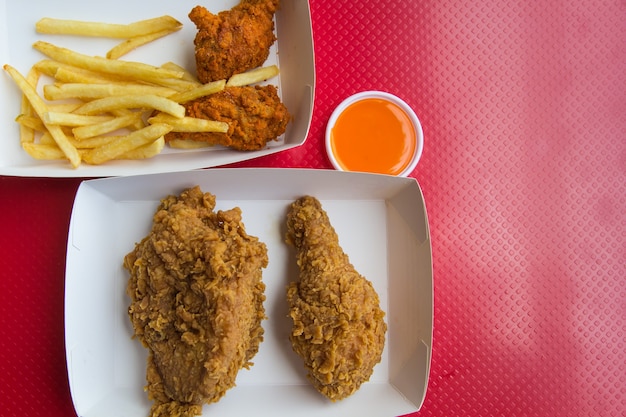 Top view fried chicken and french fries on a red background