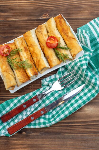 top view fried greens pastries with tomatoes inside plate