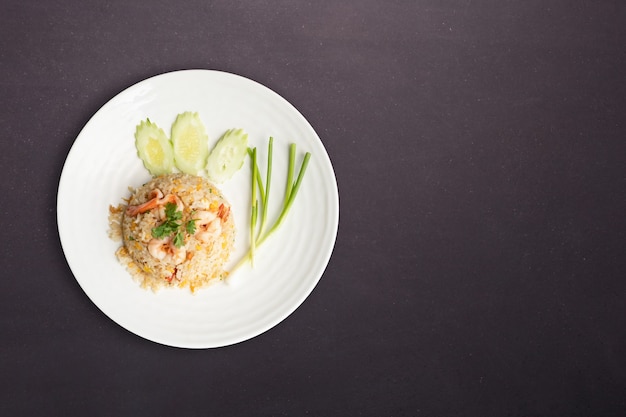 Top view. Fried rice with shrimp in round white dish isolated on black nature stone background. Thai Food concept