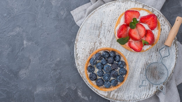 Photo top view of fruit tarts with sieve and copy space