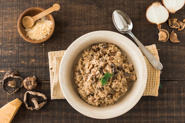 Top view of fungi risotto dish with ingredients on wooden table