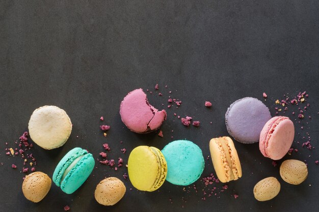 Top view funny colorful macaroons on black background