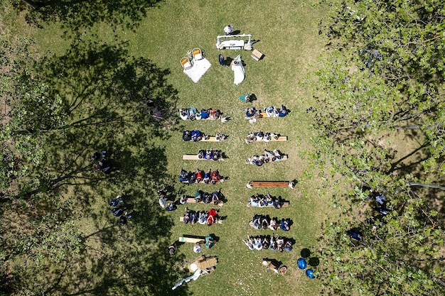 Top view of a garden wedding ceremony with people gathered to the event before the altar