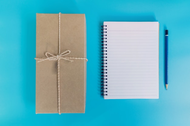 Top view of gift box and notebook on blue background