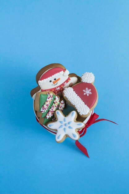 파란색 배경에 크리스마스 쿠키가 있는 선물 상자의 상단 보기. 공간을 복사합니다. 위치 수직.