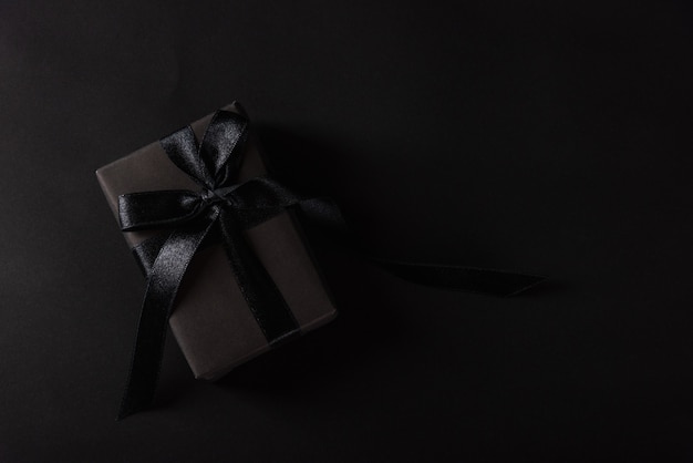 top view of gift box wrapped in black paper and black bow ribbon