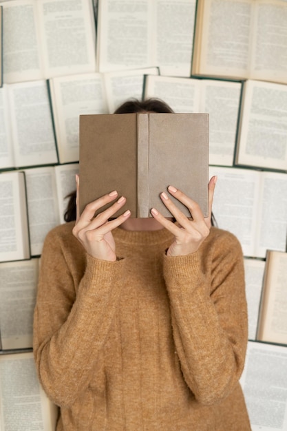 Top view a girl in a cozy soft sweater lies on open books