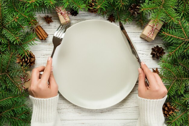 Top view girl holds fork and knife in hand and is ready to eat. 