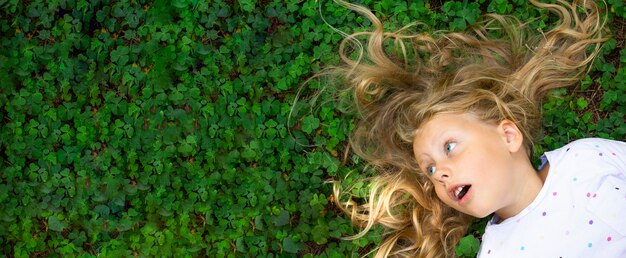 Top view on girl with blond hair on green grass