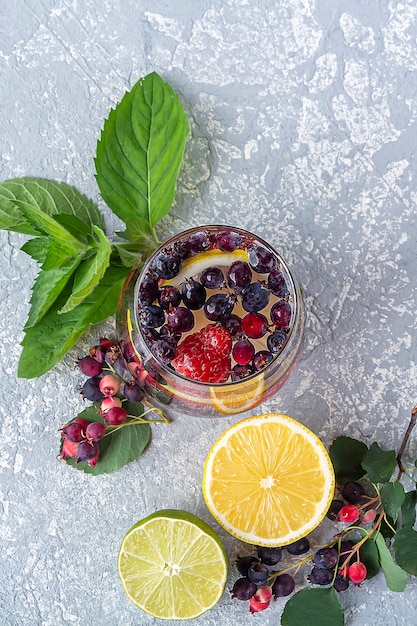 Top view of glass of detox drink with berries and lemon on concrete background