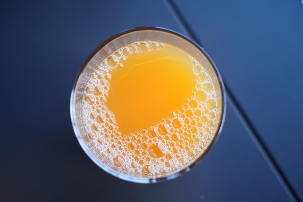 Top view of a glass of orange juic with bubble on table