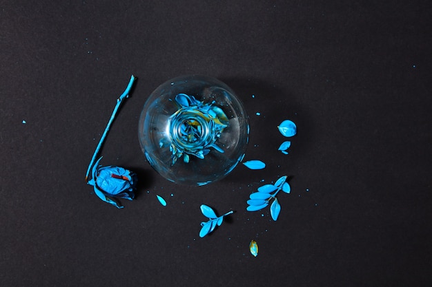 Top view of a glass vase with blue painted leaf and dry rose